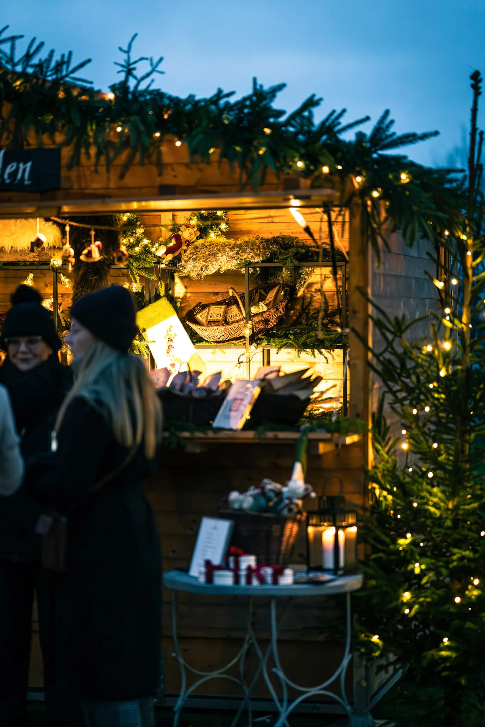 Julmarknadsstuga med varor och granris i den öppna luckan