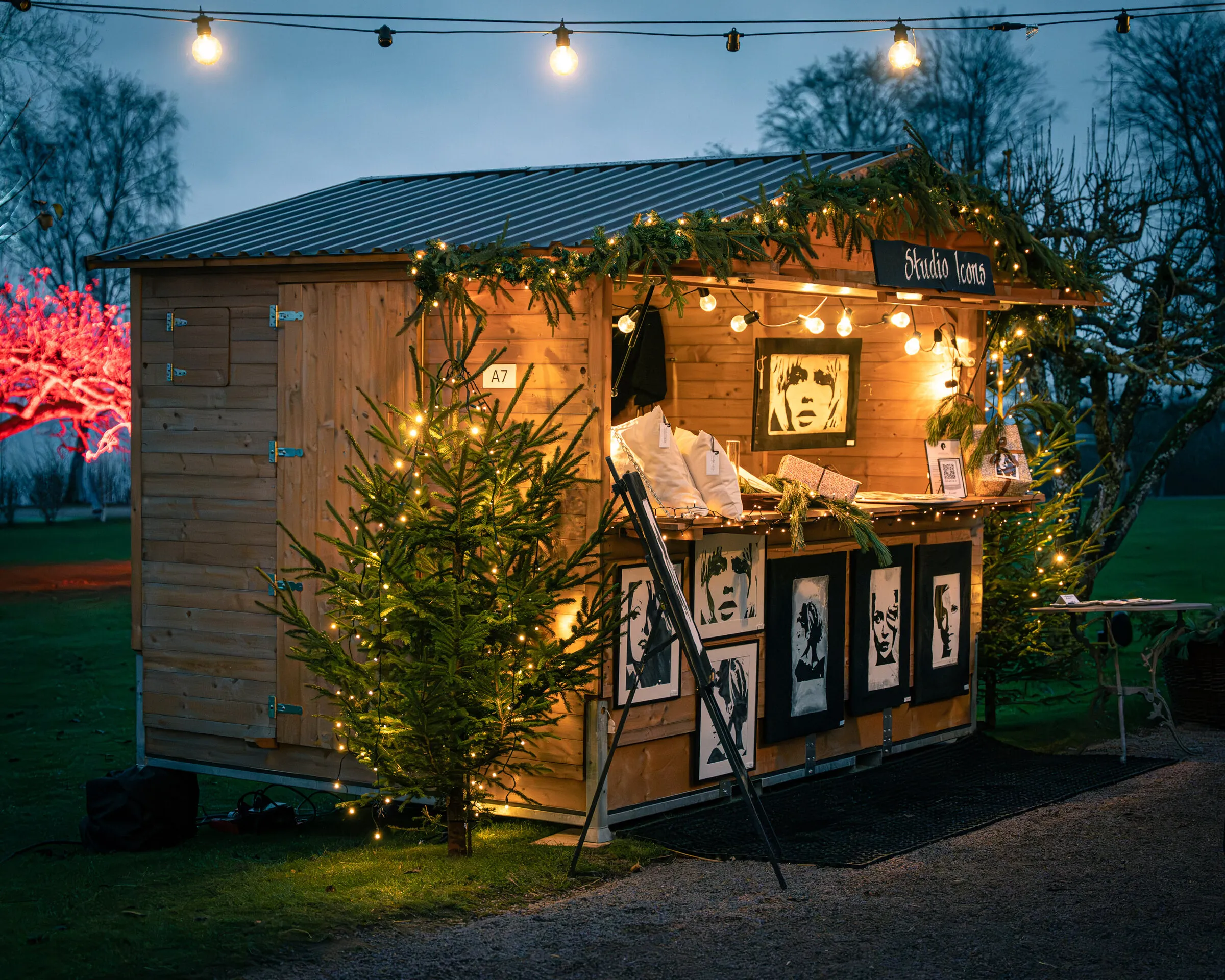 Julmarknadsstuga med tavlor i luckan och ljusslinga ovanför
