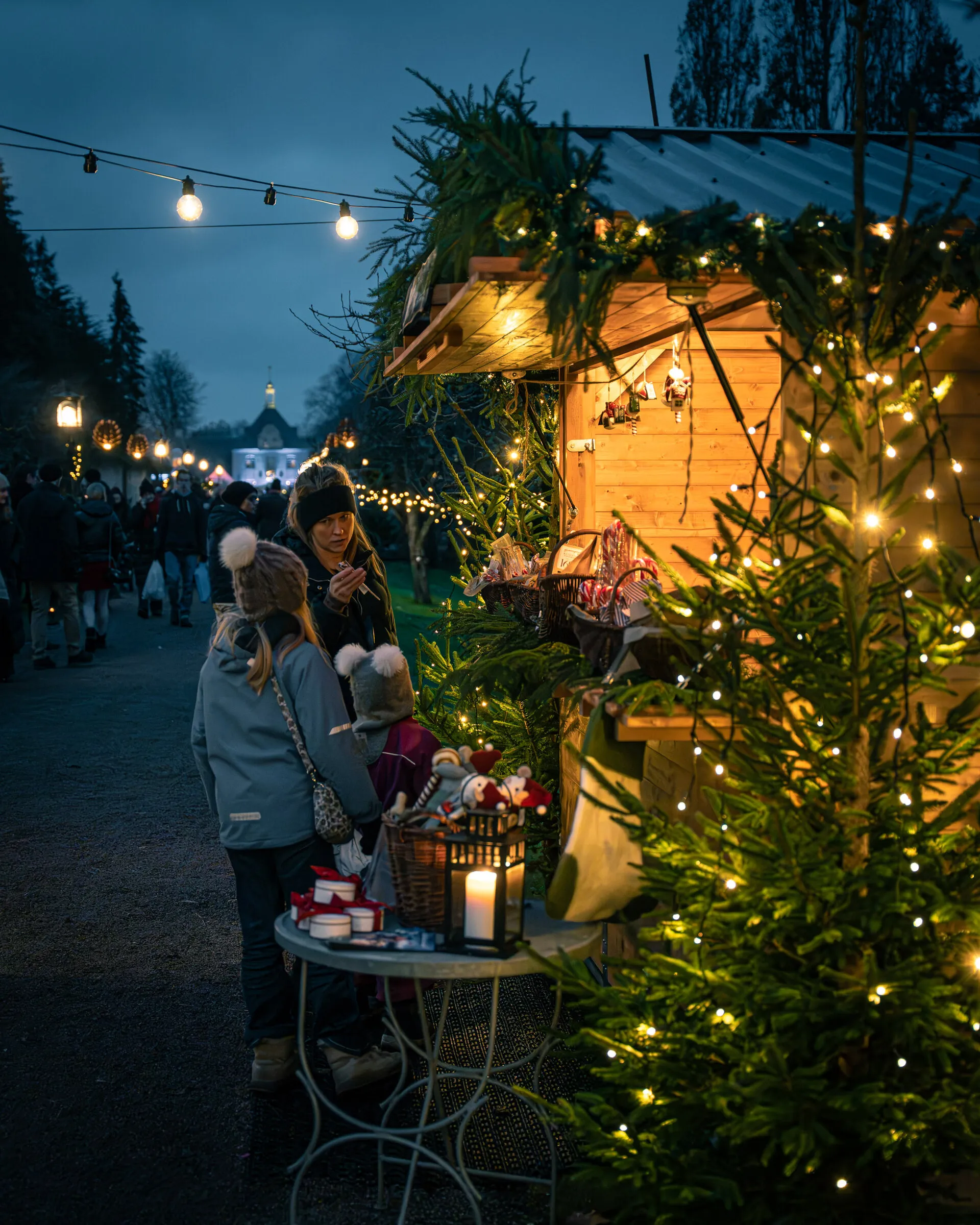 Julmarknadsstugor längs en gång med ljusslingor