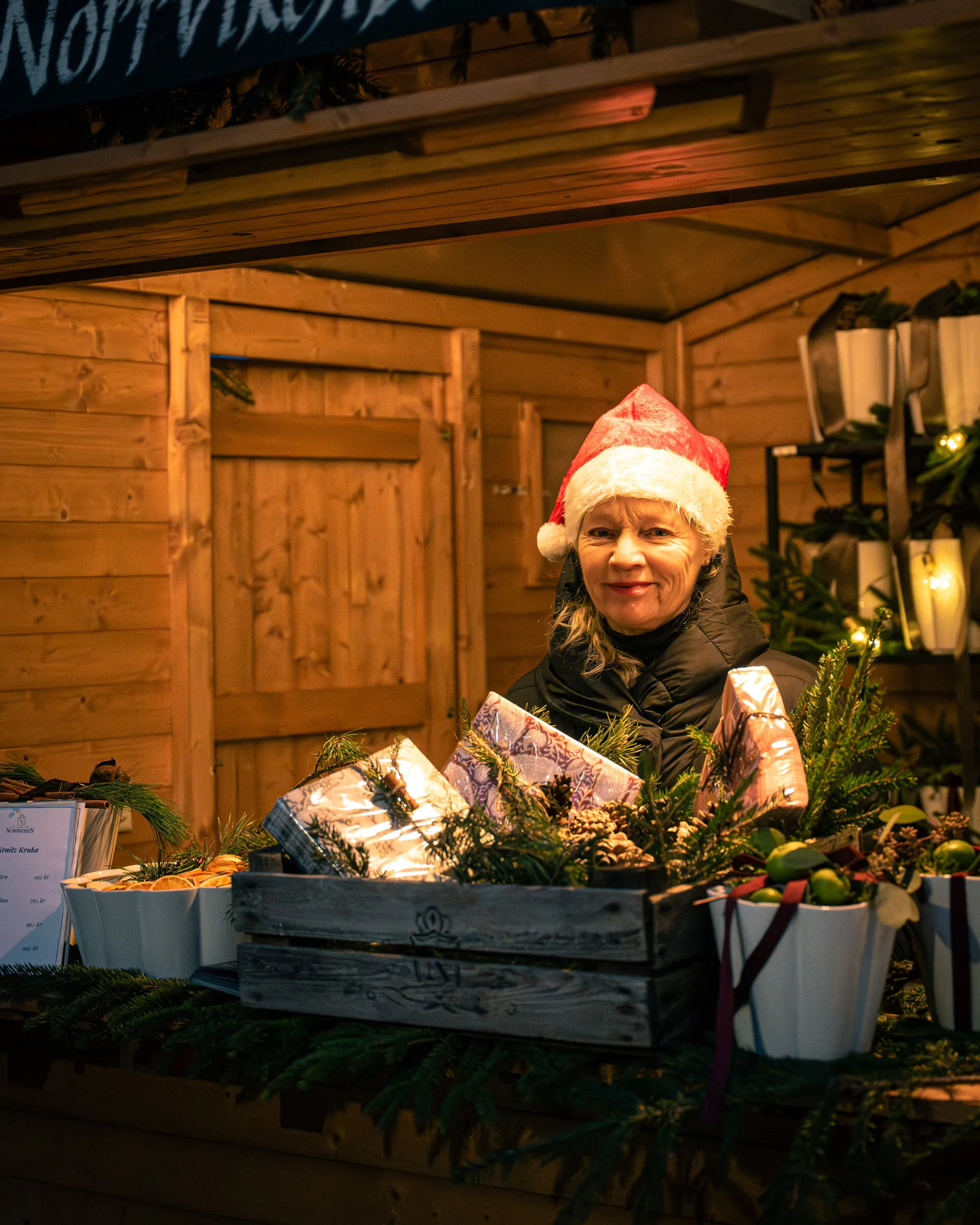 Säljare i tomteluva i en julmarknadsstuga