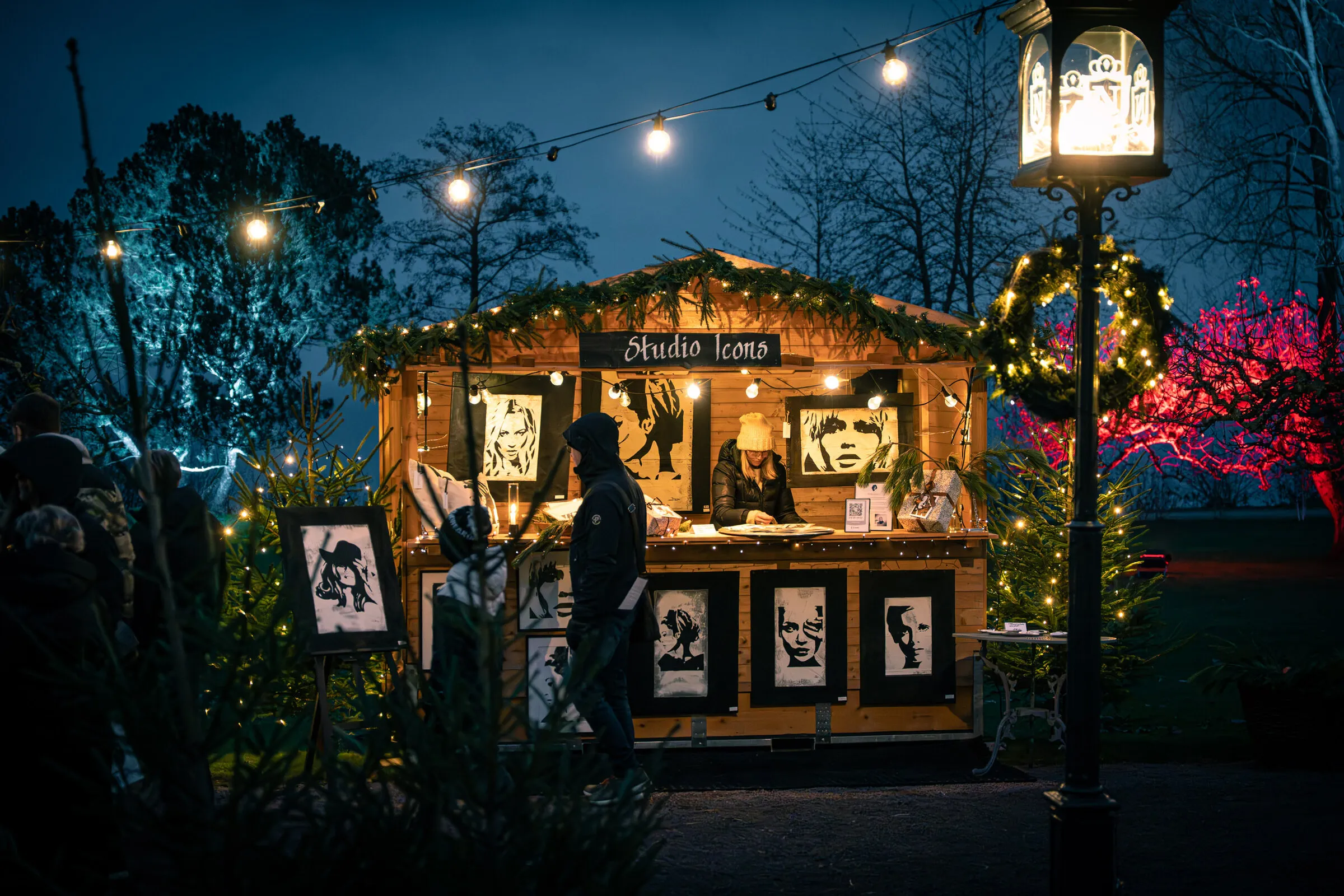 Julmarknadsstuga med tavlor och en lykta framför