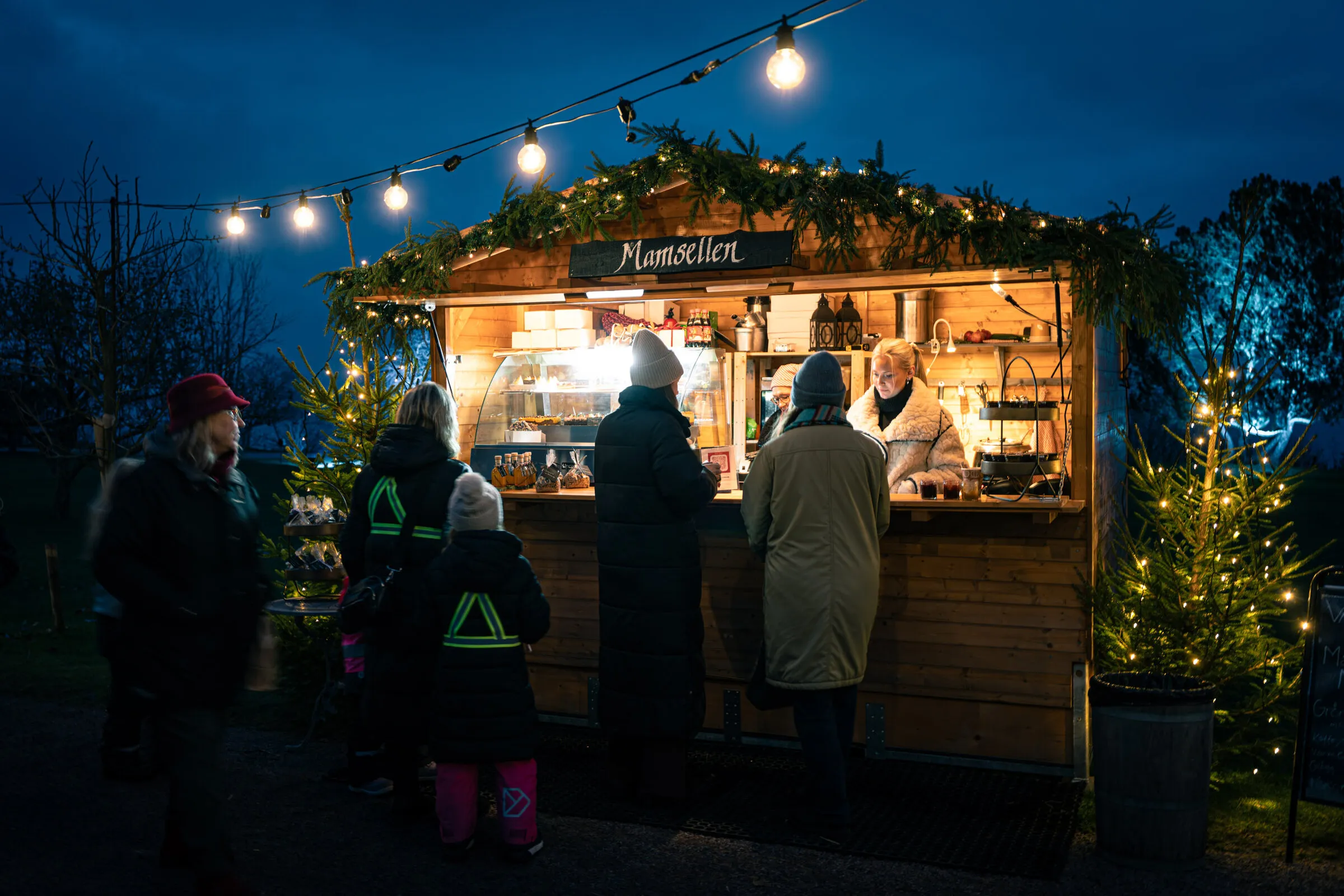 Besökare handlar i en julmarknadsstuga med öppen lucka