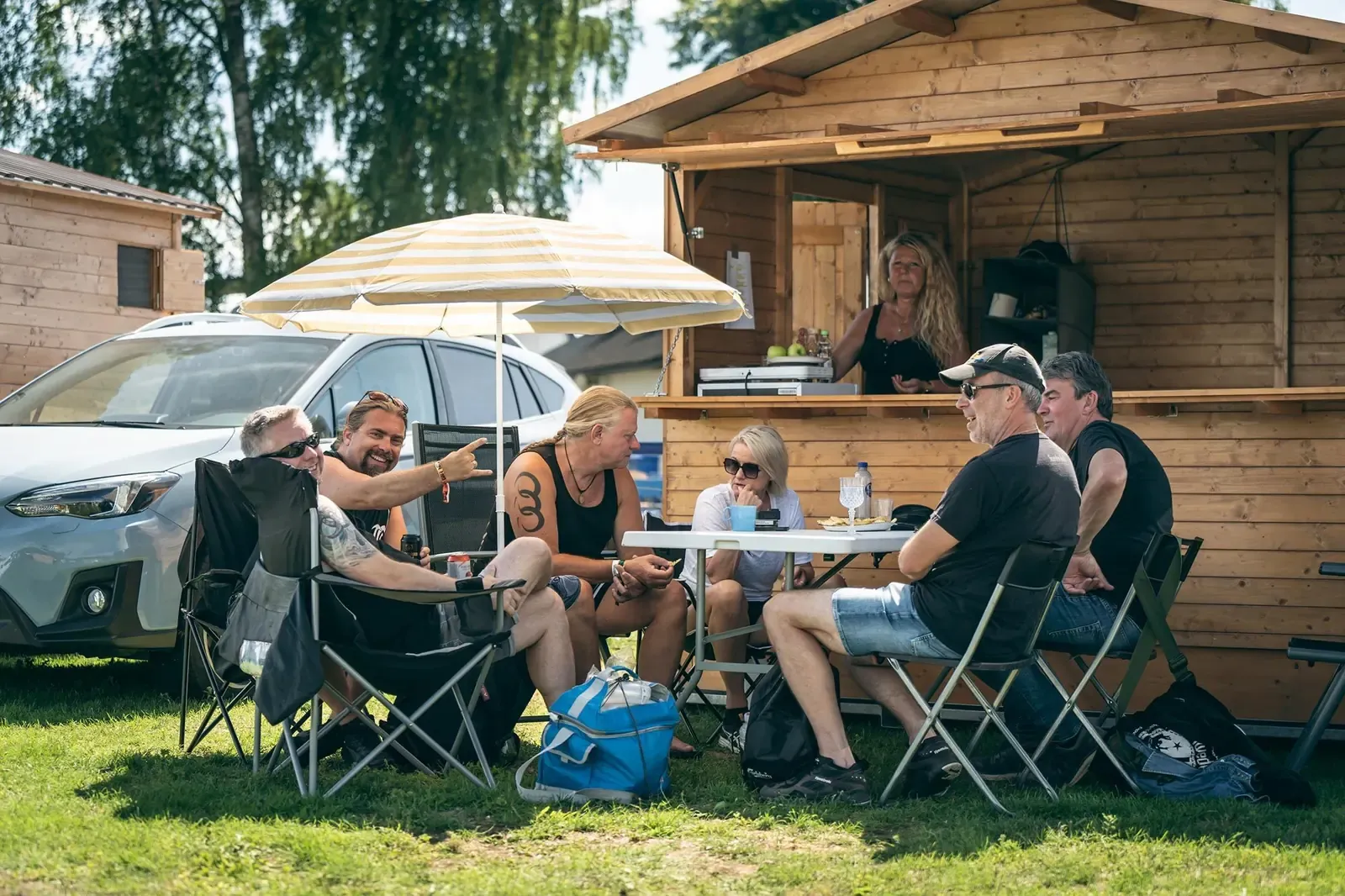 Festivalbesökare i solen framför stugorna på Time to Rocks camping